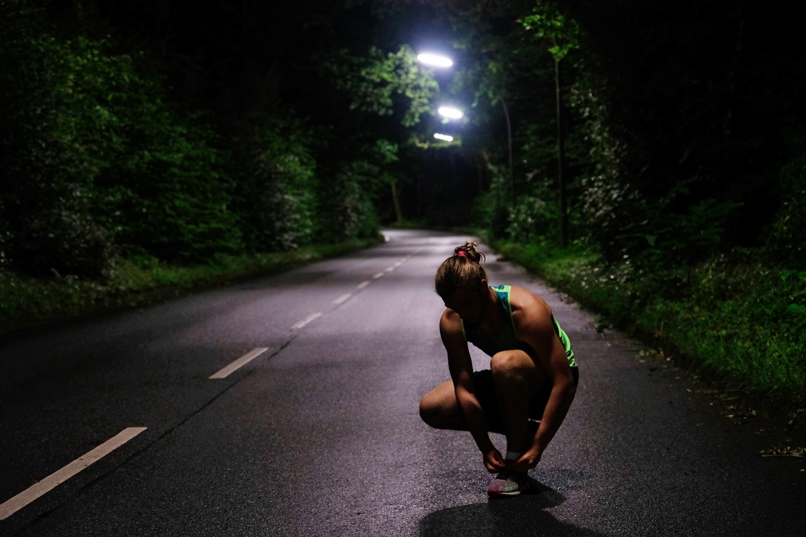 a woman squatting down on a road at night